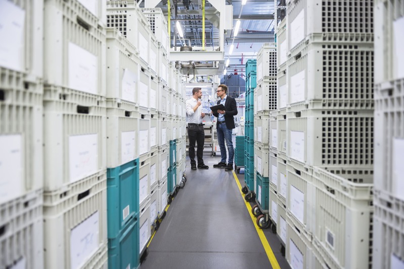 two-men-with-tablet-talking-at-boxes-in-factory