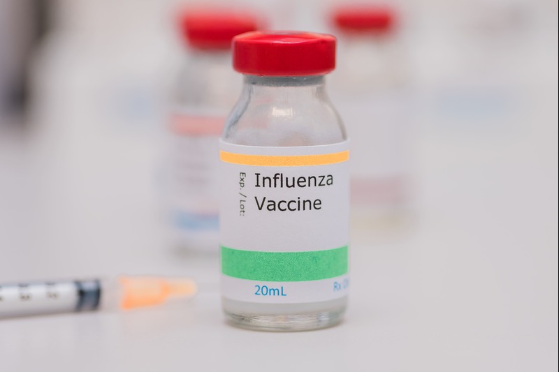 Flu shot vaccination concept, influenza vaccine vial sitting on doctors desk. Image by rohaneh, Envato