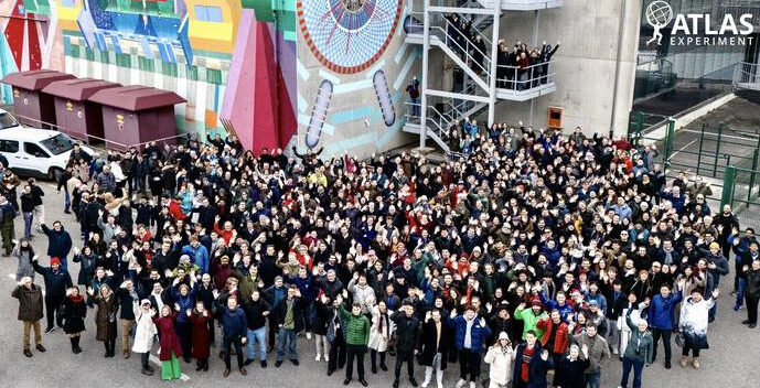 Part of the members of the ATLAS collaboration in front of the ATLAS experiment mural (1:3 scale) and ATLAS control room located at CERN, 100 meters above the experiment cavern. Credit: M. Struik/CERN